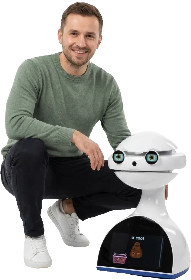 Michał przykucnięty obok białego robota Emys